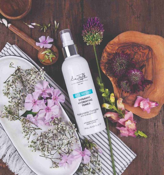 White bottle of dynamic hydrating toner with flowers and wooden elements on a wooden surface