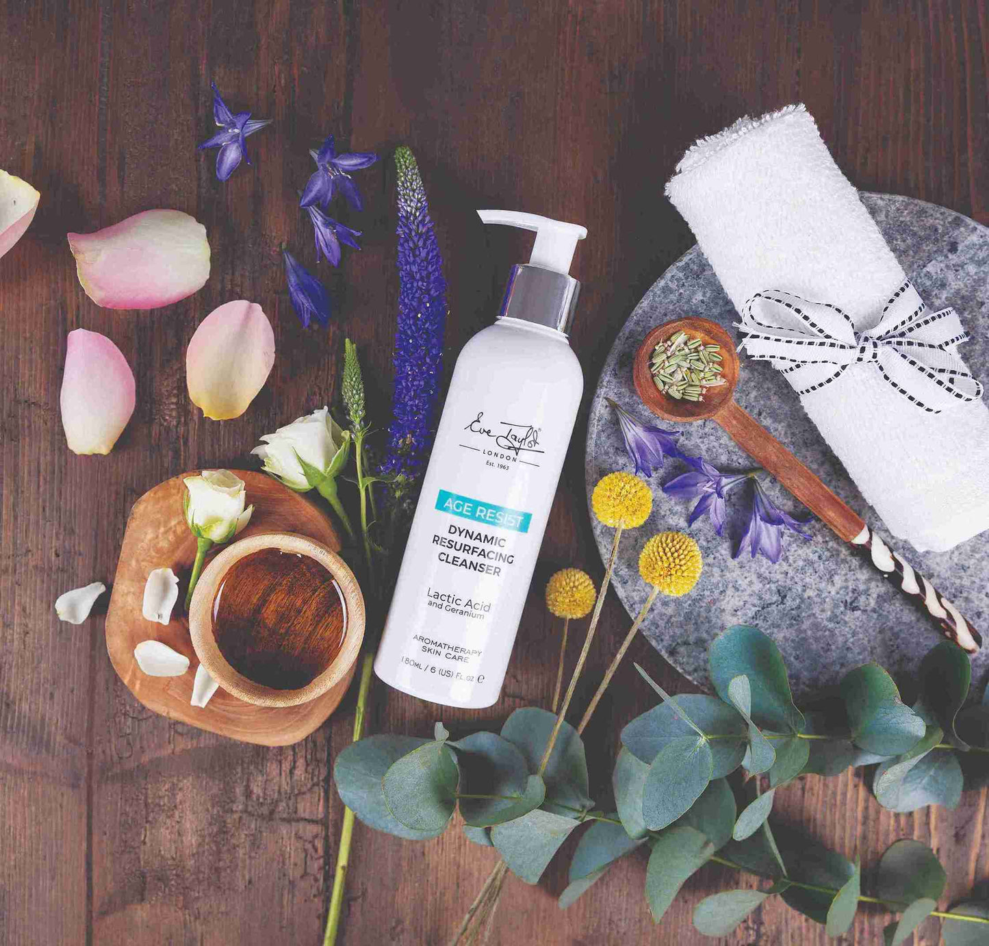 Skincare product with flowers and natural elements on a wooden surface