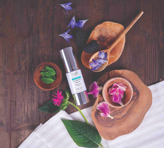 Skincare serum bottle on a wooden surface with flowers and leaves