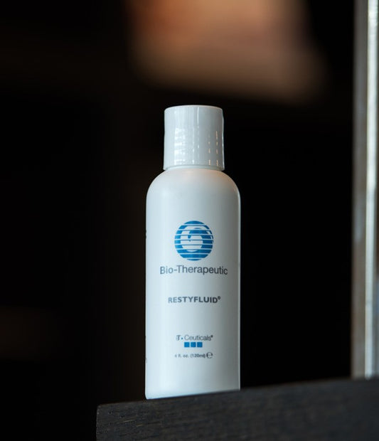 Bio-Therapeutic RestyFluid bottle on a dark surface with a blurred background