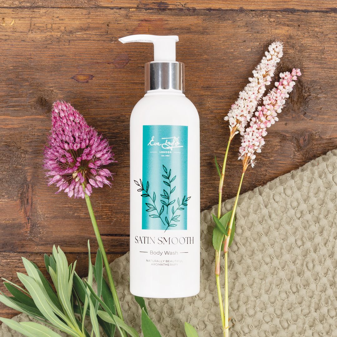 Body wash bottle with silver pump, white bottle with teal botanical label.