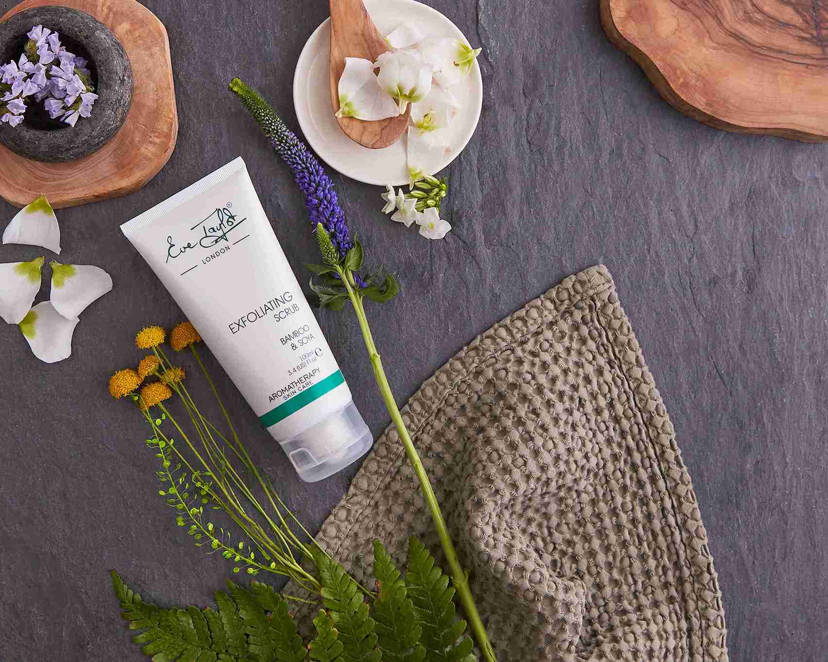 Skincare product with flowers and a towel on a dark surface