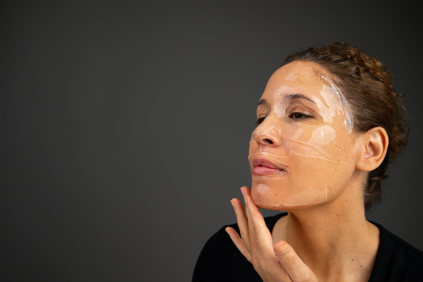 Hydrating facial mask sheet with white gel patches on woman's face