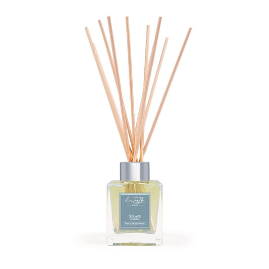 Natural reed diffuser with square clear glass bottle, label, and light tan reeds.